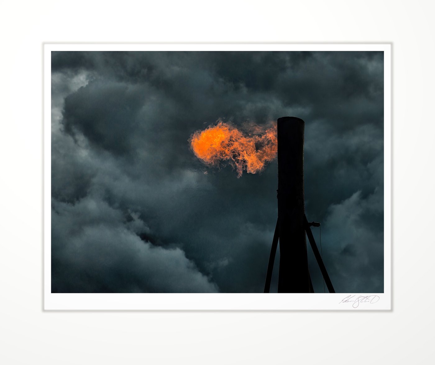A dramatic natural gas pipe burn off against dark storm clouds. Eaton Rapids, Michigan -September, 2013