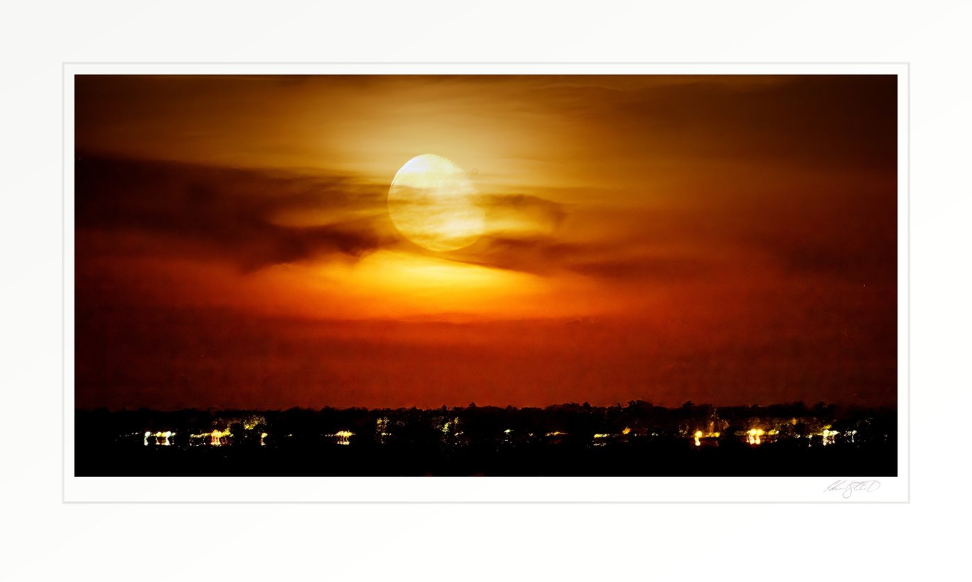 A firey full moon rising into a smoky orange sky above Lake Huron and the lights of Caseville. -October, 2024