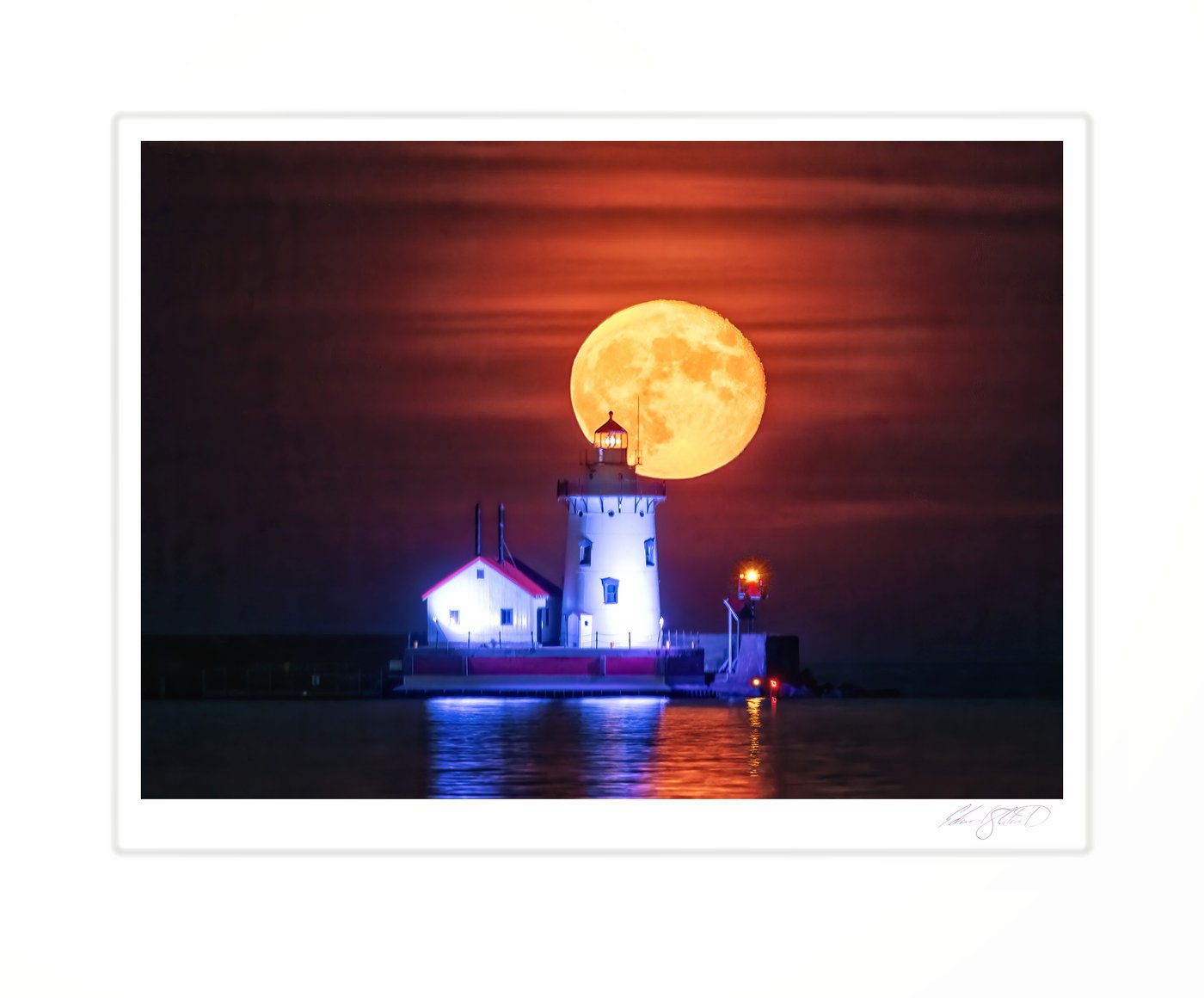 A huge full moon rising behind Harbor Beach lighthouse against an orange sky. Harbor Beach, Michigan -September 30, 2023