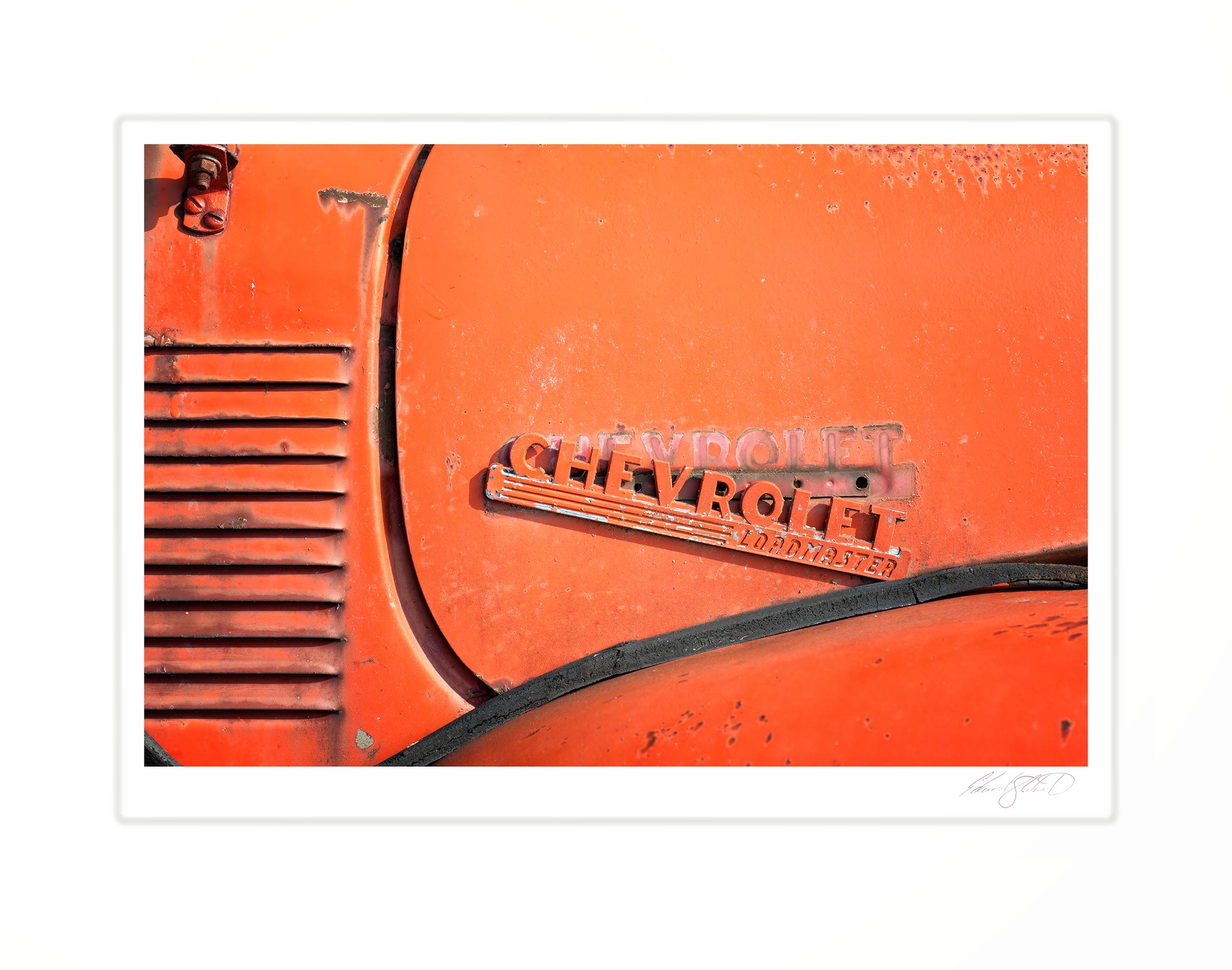 A close-up of a rusted orange Chevrolet Loadmaster emblem. At the fish docks, Naubinway, Michigan -March 2011
