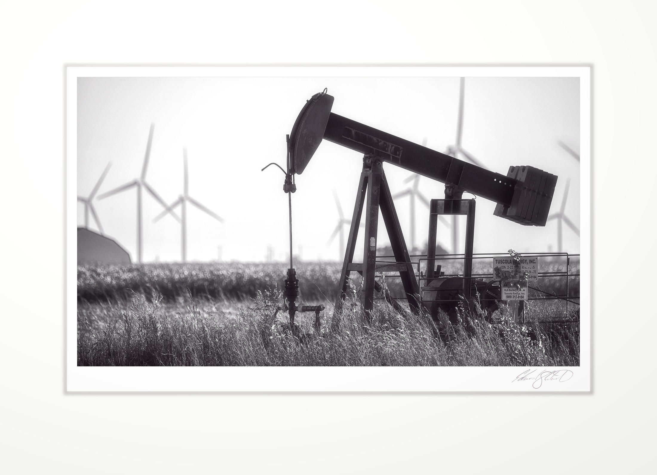 An oil pumpjack with wind turbines behind. Wisner, Michigan -October 2018
